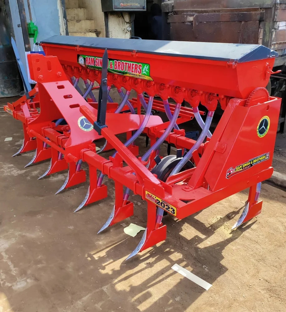 Red tractor-mounted seed drill machine used for uniform seed planting on farms in Tanzania.